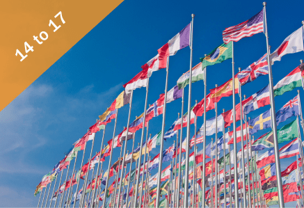A myriad of flags from different countries against a blue sky.