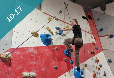 Person on a climbing wall smiling at the camera.