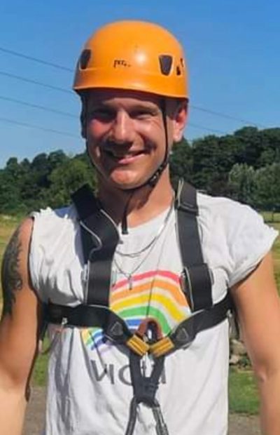danny Danny smiles in a climbing harness and helmet at a VICTA activity