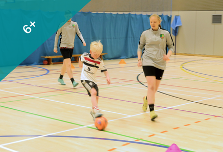 Child playing partially sighted football on an indoor court.