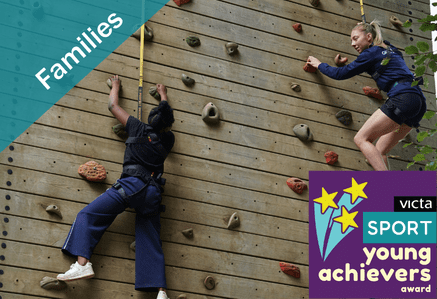Two people climbing an outdoor climbing wall.