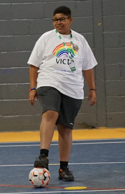 alex-day Alex wears a VICTA t-shirt. He stands with a football under his right foot.