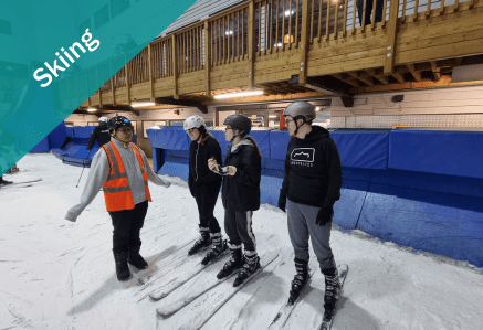 Three young people and an instructor wearing skis in the snow.