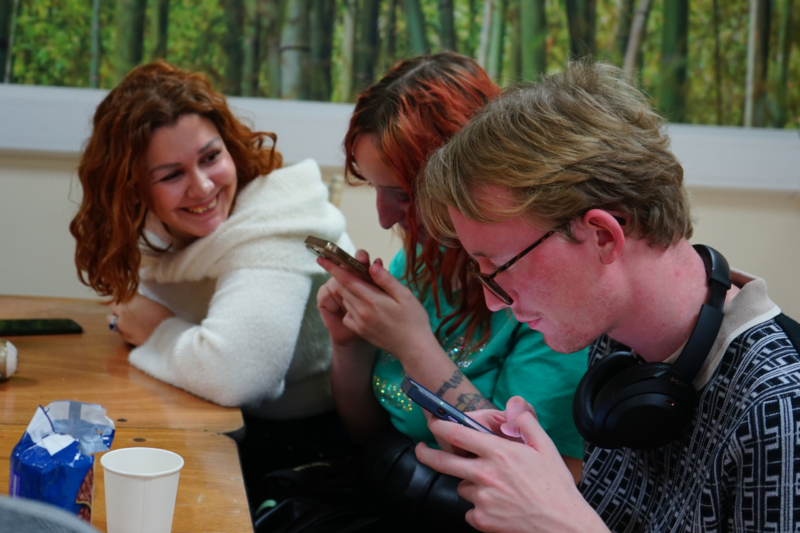 millie-jerri-james Two changemakers practice on their phones as another looks on smiling