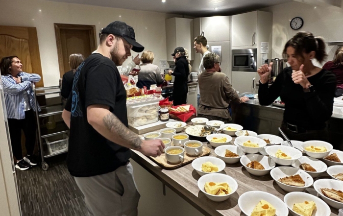 A delicious looking selection of desserts with people ready to serve them on trays