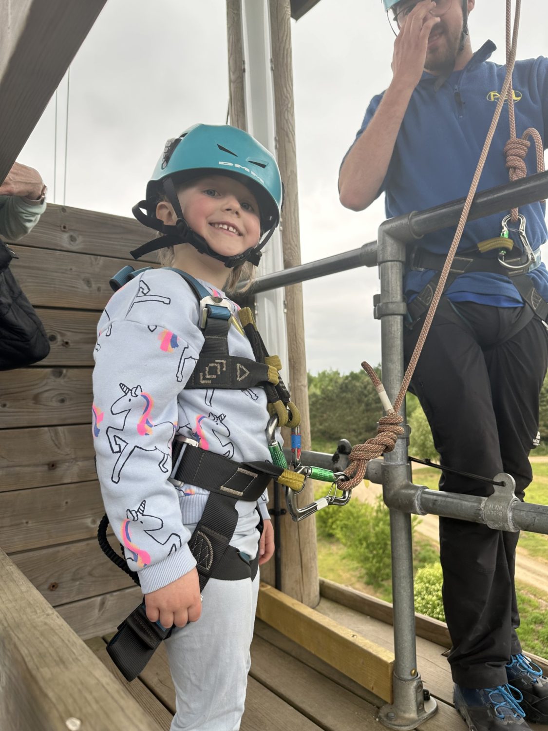 A girl smiles - she is kitted out in a climbing harness ready to abseil