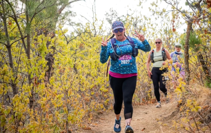 Katie running through a wooded area at an organised event