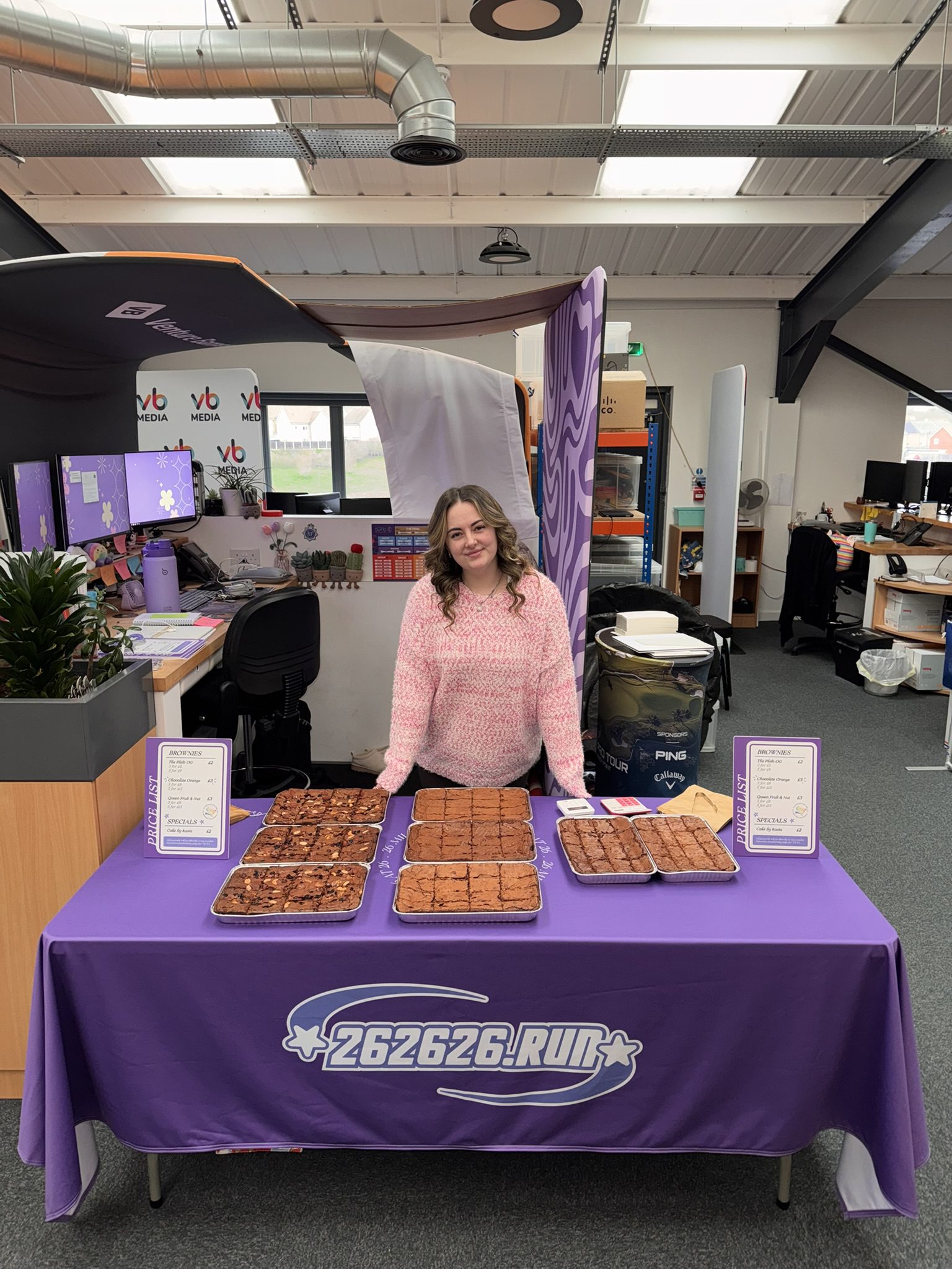 Kayleigh stands behind her table with the trays of brownies