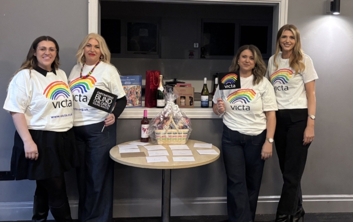 4 fundraisers stand in VICTA t-shirts next to the prize table