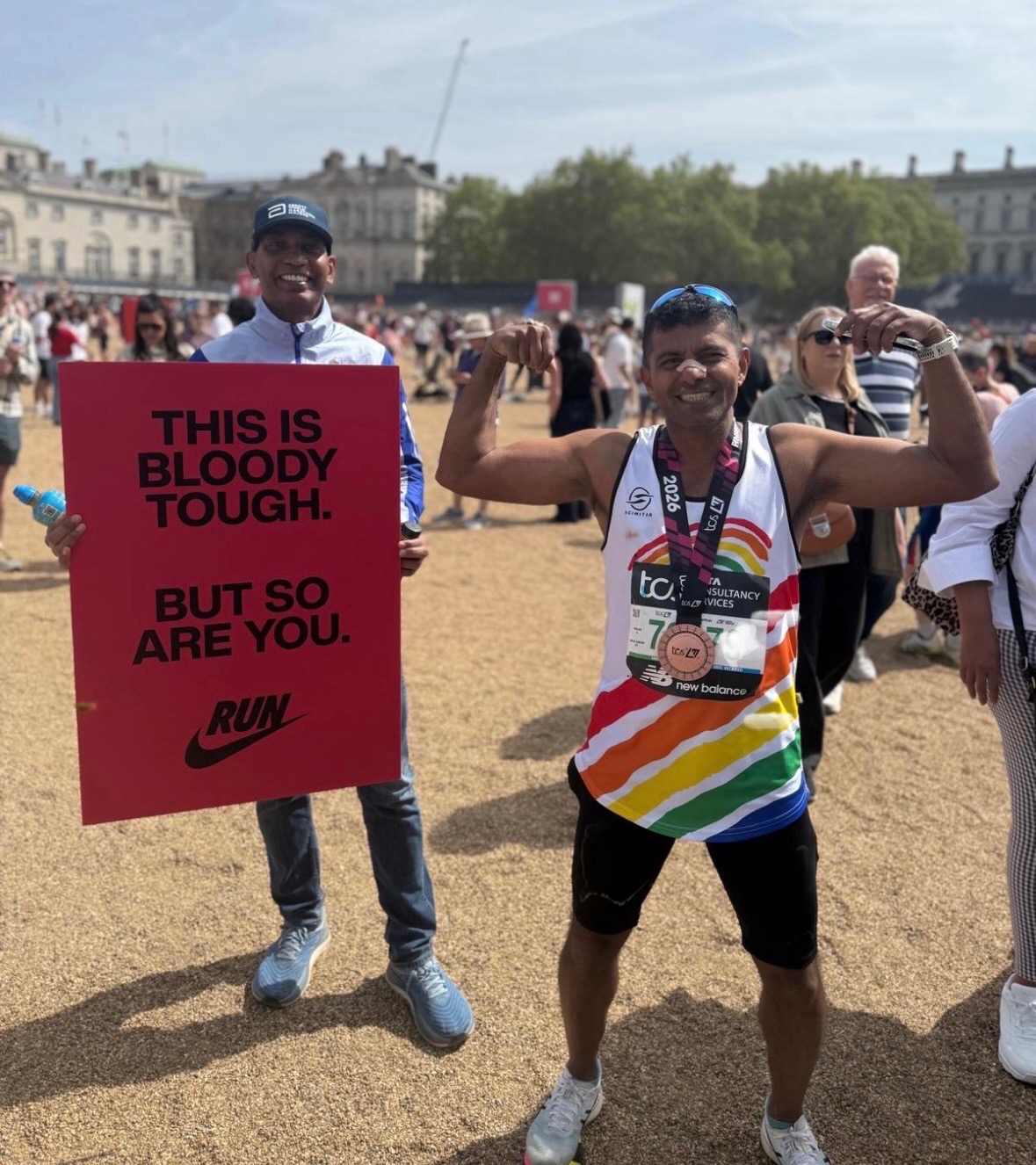 Santhosh A VICTA runner does a strong man pose next to a sign that reads - this is bloody tough but so are you!