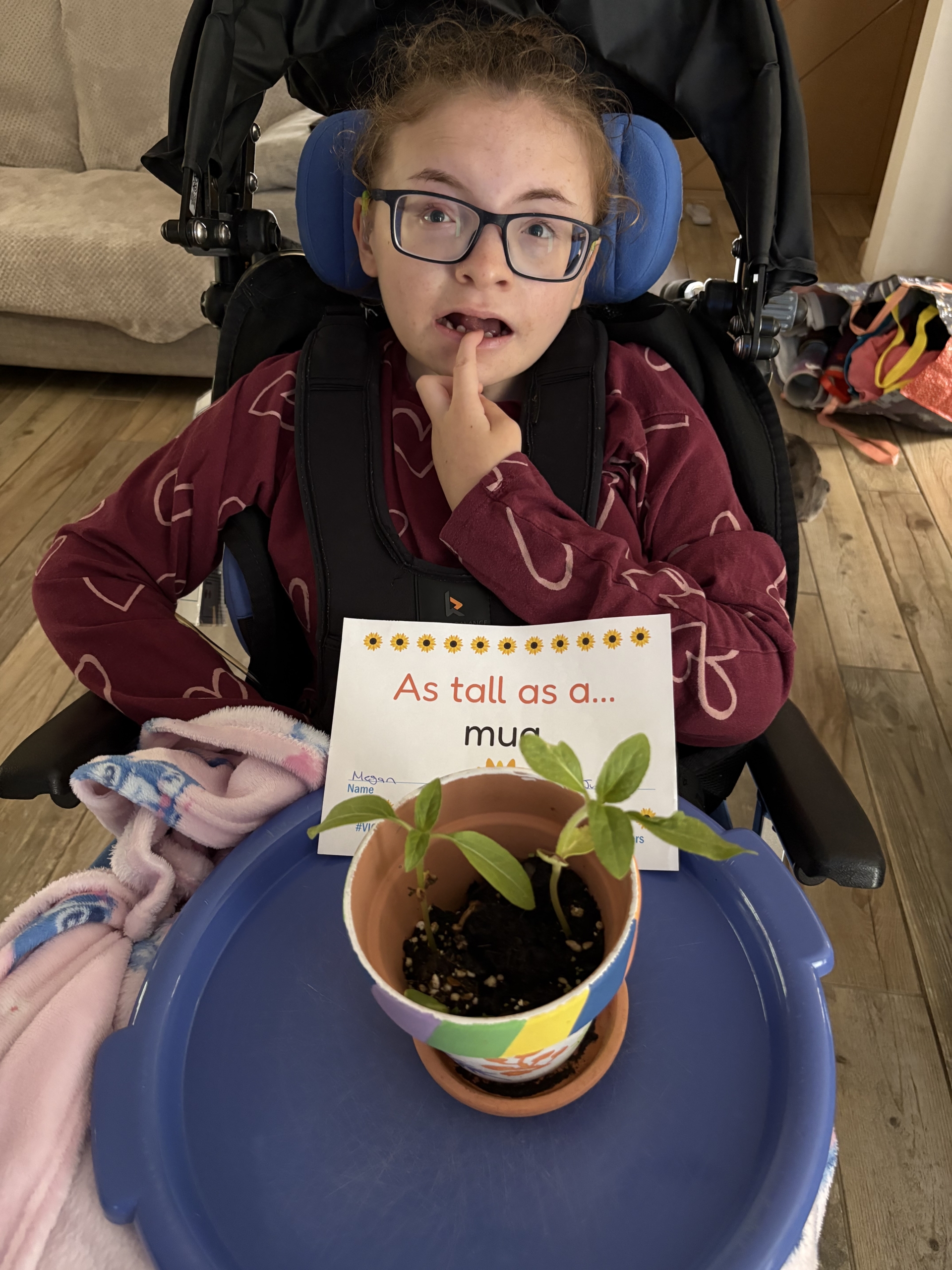 Megan mug Girl holding a potted sunflower on her knee.