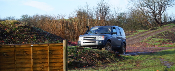 DSC00021 A 4x4 car off roading through green countryside - it is approaching a small hill.