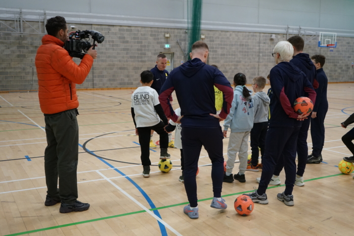 DSC09939 Coaches talk to the children as a camera man films