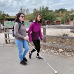 Two teenagers walk together at Summer Camp - one uses a white cane
